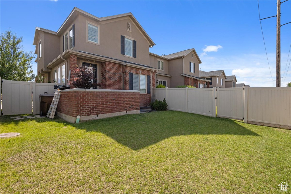 Rear view of property with a gate, brick siding, and stucco siding