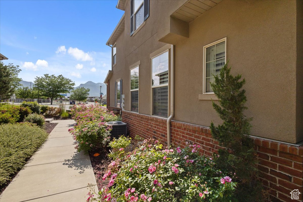 View of side of property with stucco siding, brick siding, a mountain view, and cooling unit