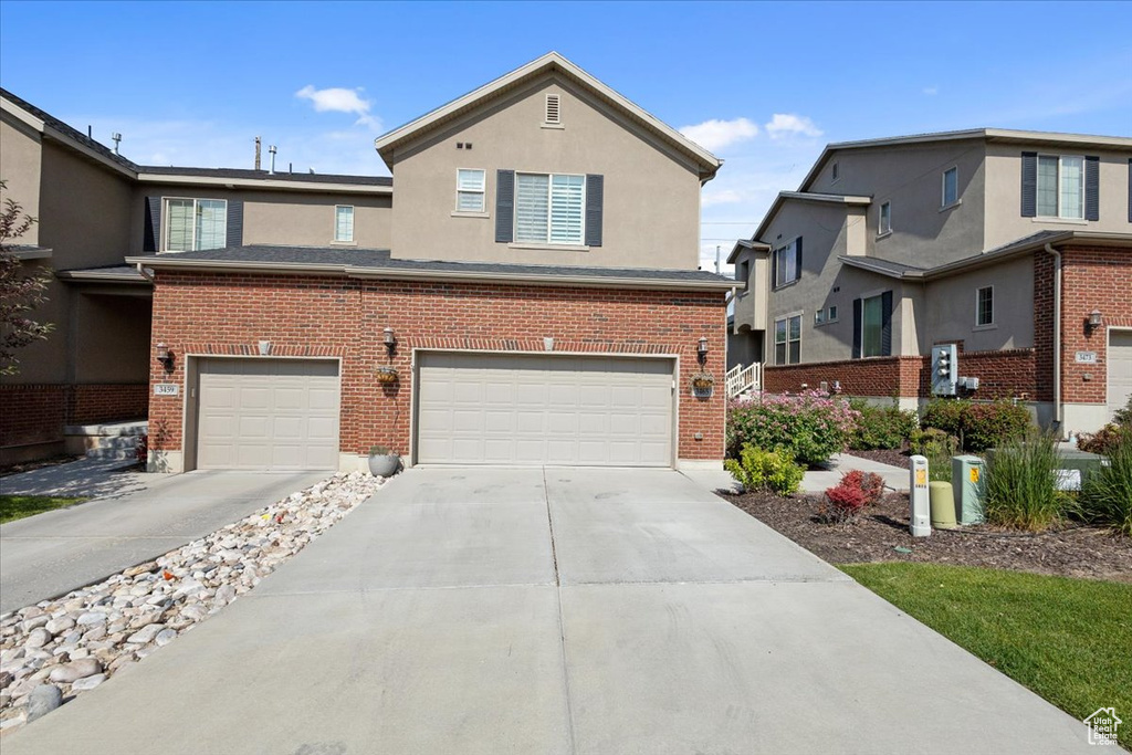 Traditional-style home featuring a garage, concrete driveway, and stucco siding