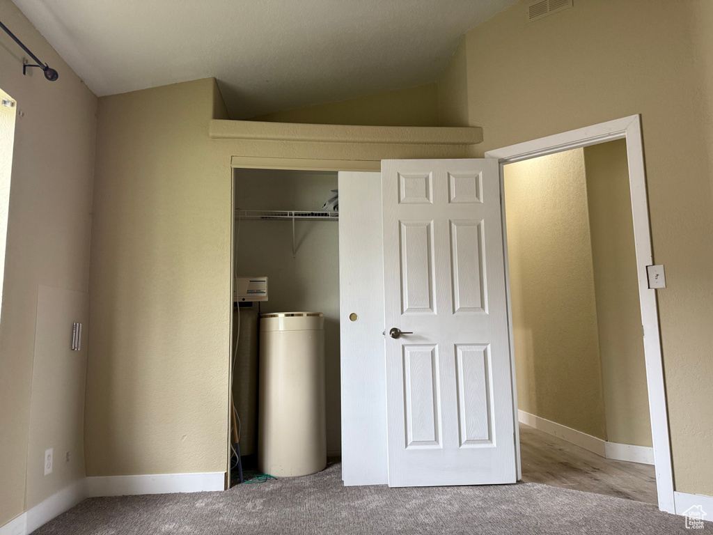 Unfurnished bedroom featuring a closet, carpet, lofted ceiling, and baseboards