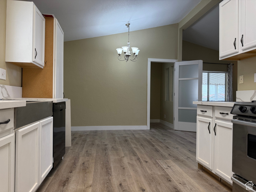 Kitchen with stove, dishwasher, lofted ceiling, a chandelier, and light countertops