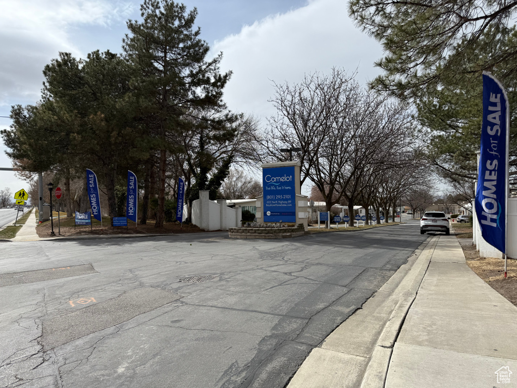 View of asphalt road featuring sidewalks, traffic signs, and curbs