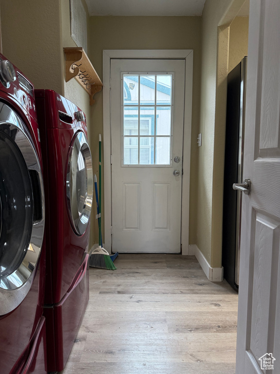 Laundry room featuring washing machine and clothes dryer and light wood-style floors