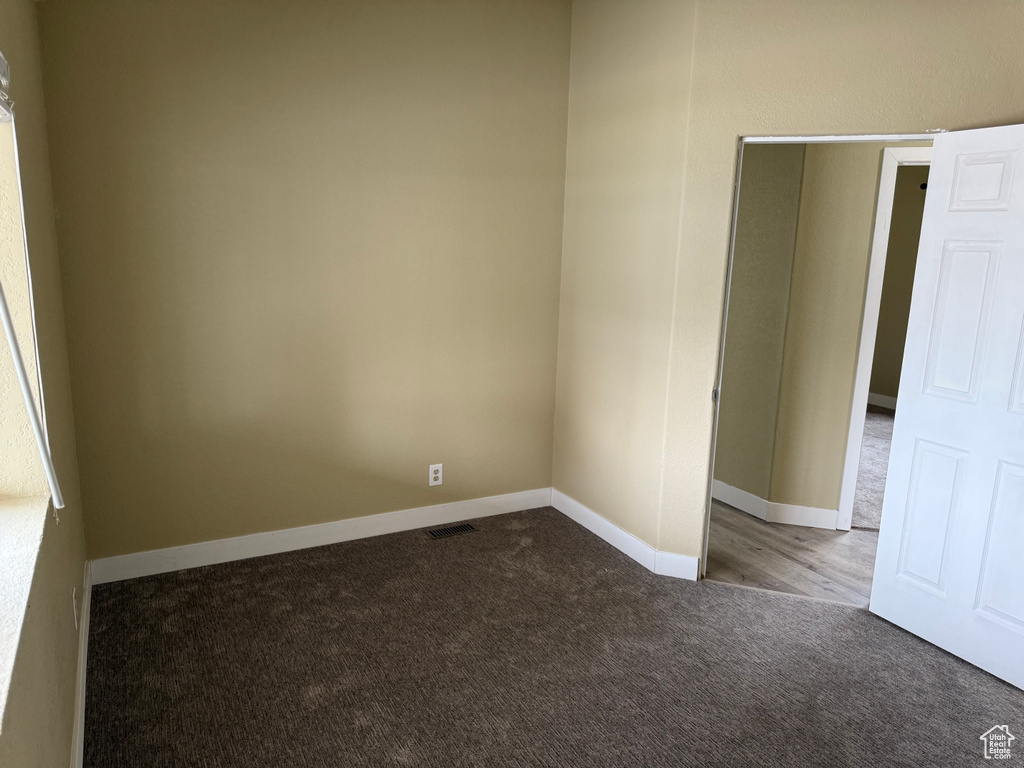 Empty room featuring dark carpet and baseboards