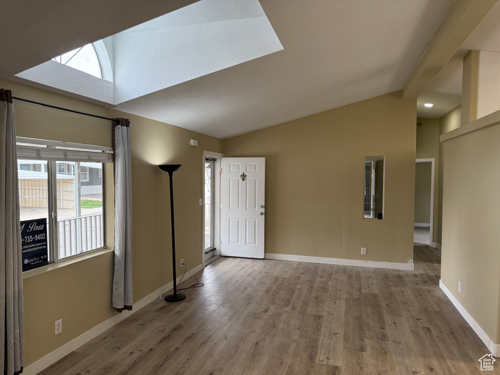 Unfurnished living room with a skylight, wood finished floors, and baseboards