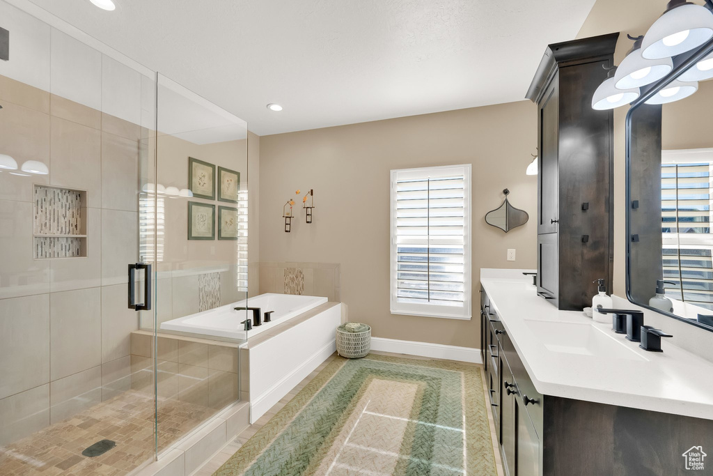Bathroom featuring double vanity, a garden tub, a shower stall, healthy amount of natural light, and recessed lighting