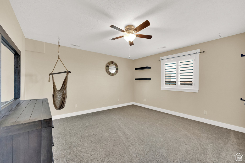 Spare room featuring a ceiling fan, carpet, and baseboards
