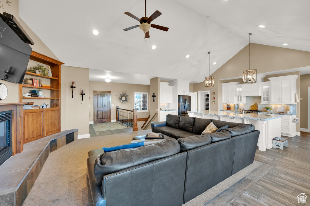 Living room featuring a ceiling fan, light wood-style flooring, recessed lighting, high vaulted ceiling, and baseboards