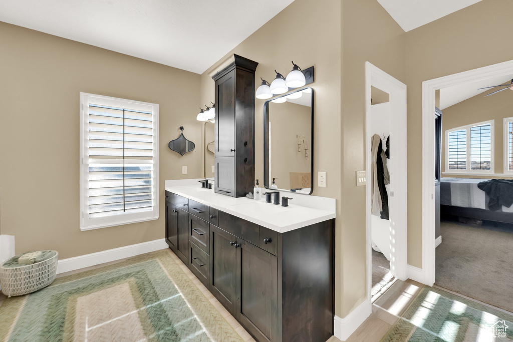 Ensuite bathroom featuring double vanity, baseboards, and ceiling fan