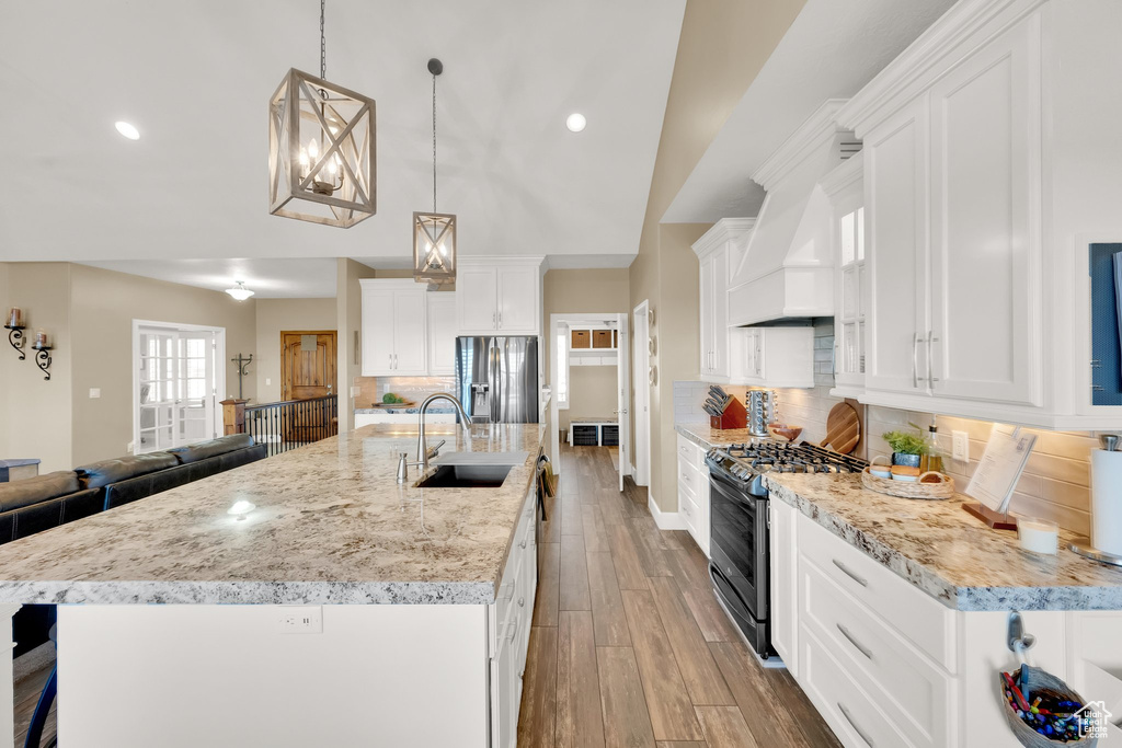 Kitchen featuring appliances with stainless steel finishes, a sink, vaulted ceiling, white cabinets, and custom exhaust hood