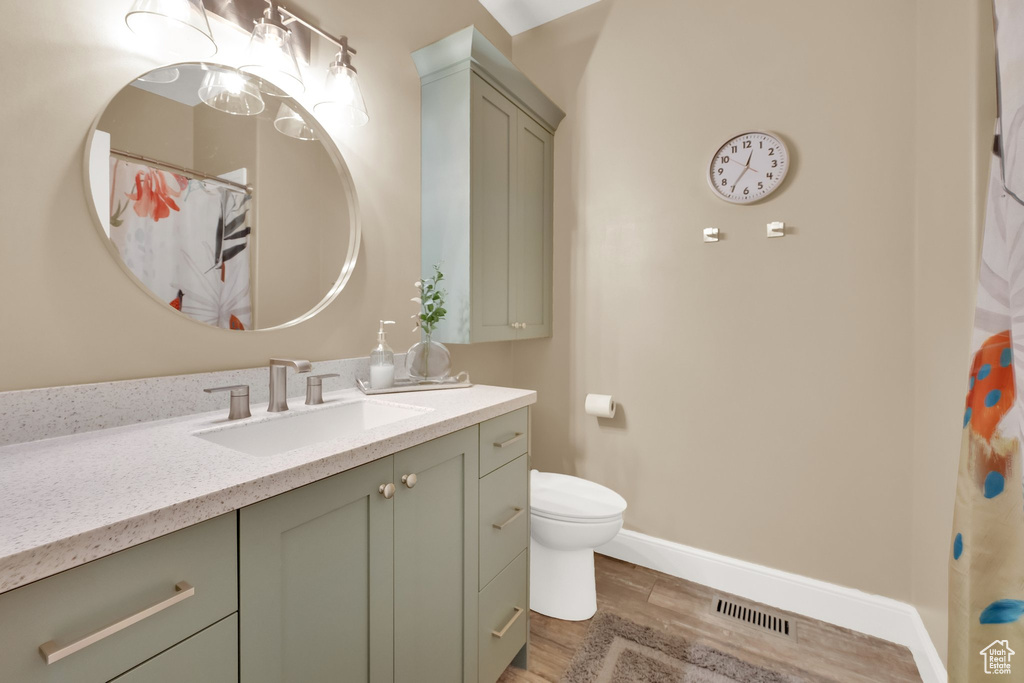 Bathroom with vanity, wood finished floors, toilet, and baseboards