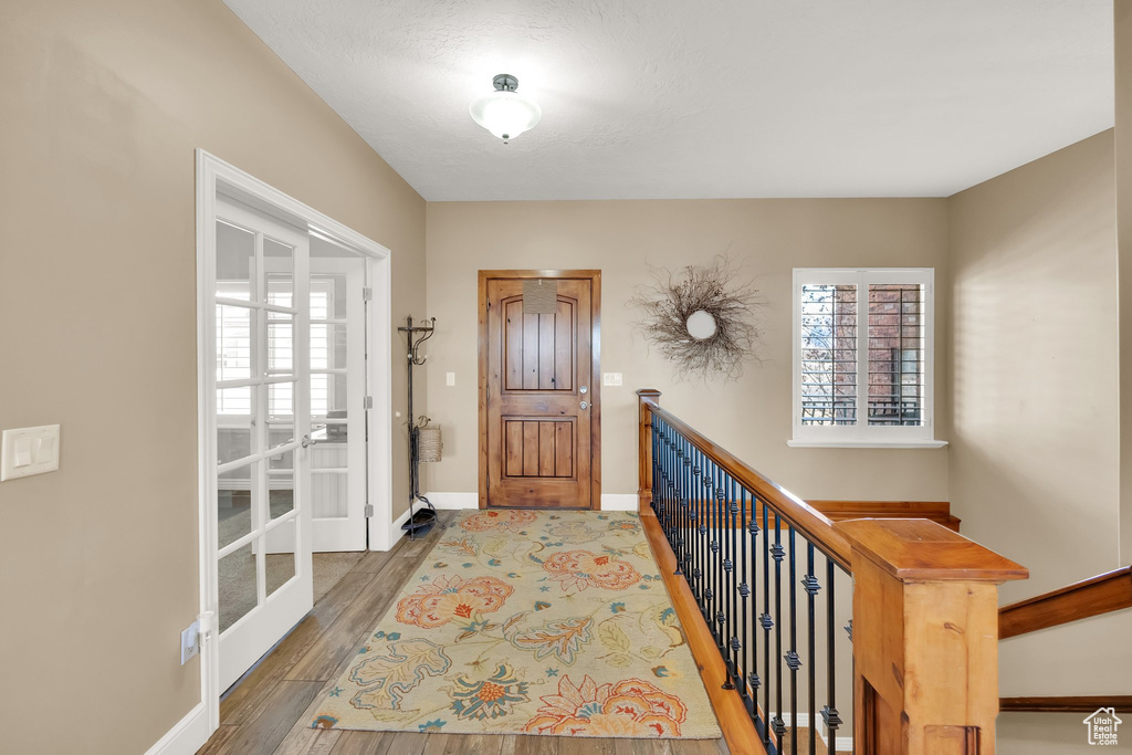 Foyer entrance featuring wood finished floors, baseboards, and french doors