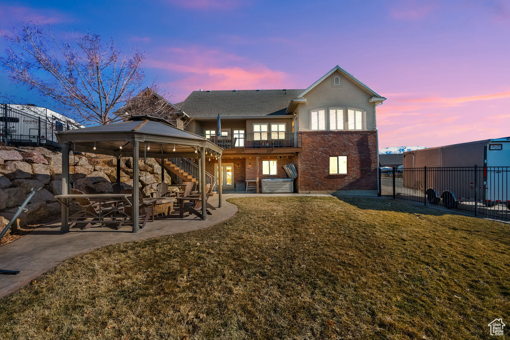 Rear view of property with a gazebo, brick siding, a patio area, stairway, and a balcony