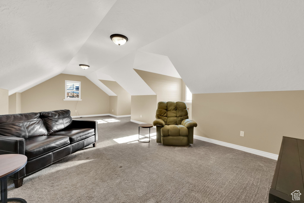 Carpeted living area featuring vaulted ceiling and baseboards