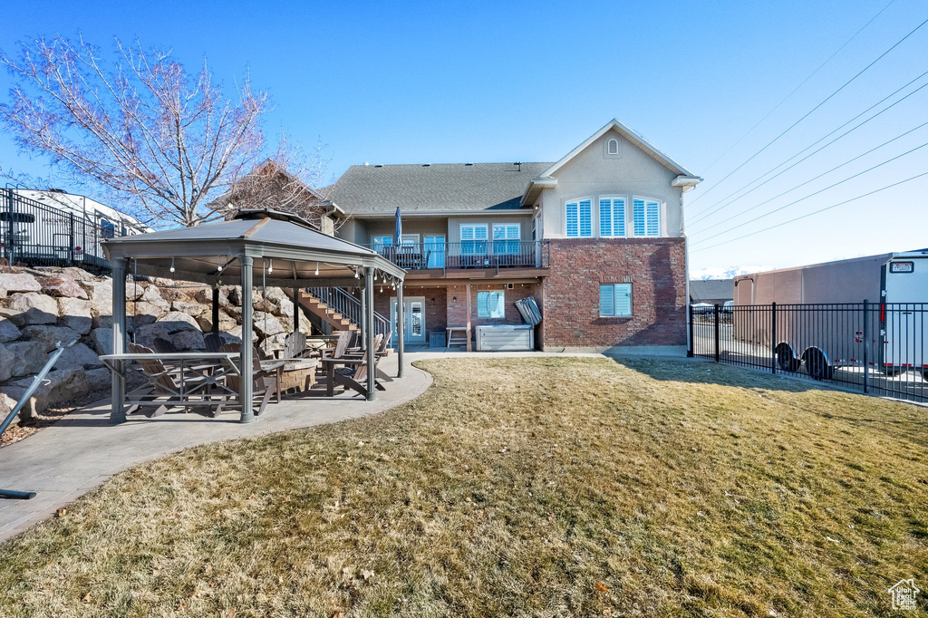 Rear view of house featuring a gazebo, brick siding, a patio area, and a balcony