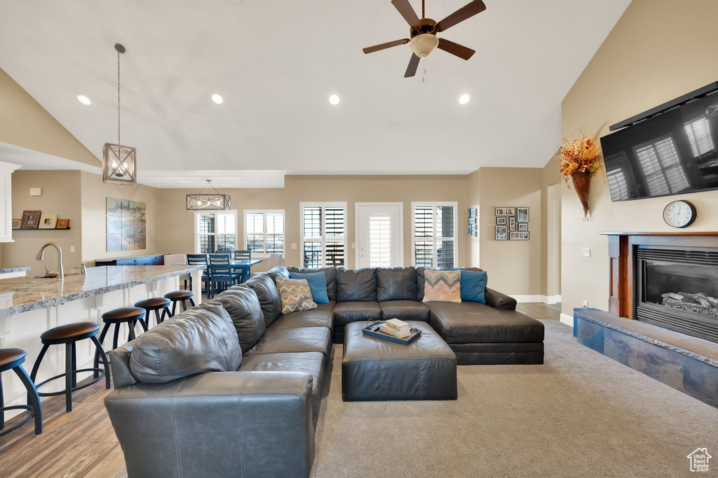 Living room featuring a glass covered fireplace, recessed lighting, ceiling fan, baseboards, and high vaulted ceiling