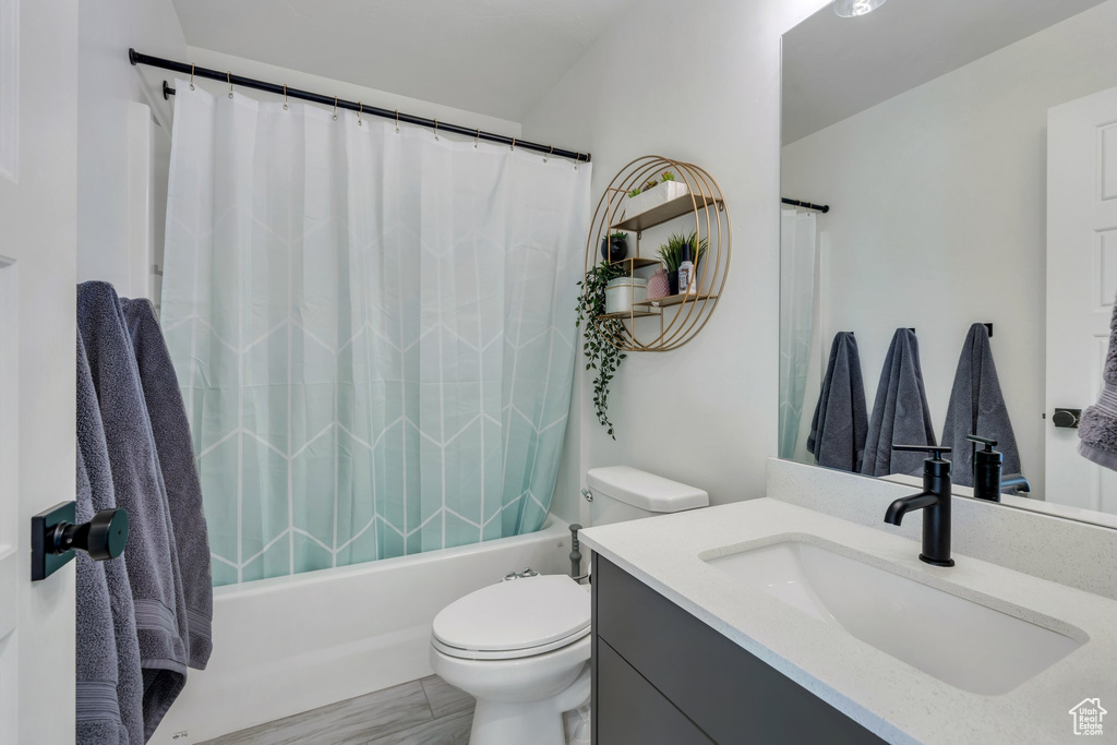 Bathroom featuring vanity, toilet, and shower / bath combo with shower curtain