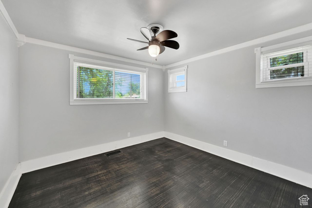 Unfurnished room featuring a ceiling fan, baseboards, and dark wood-style flooring
