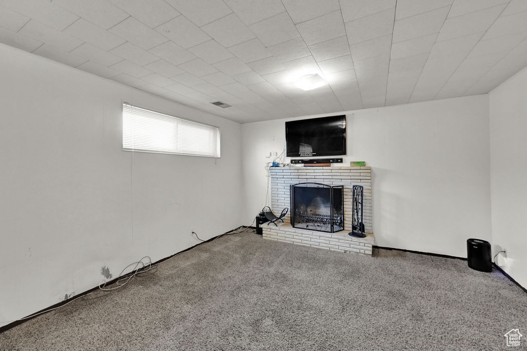 Unfurnished living room featuring carpet flooring and a brick fireplace