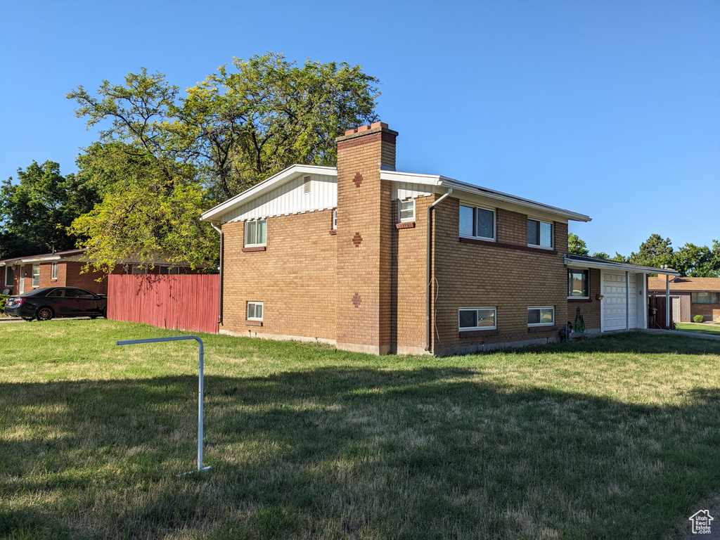 View of side of home with a chimney, an attached garage, and brick siding