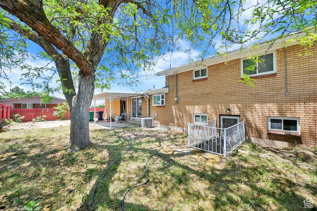 Back of house with a patio, central AC unit, and brick siding
