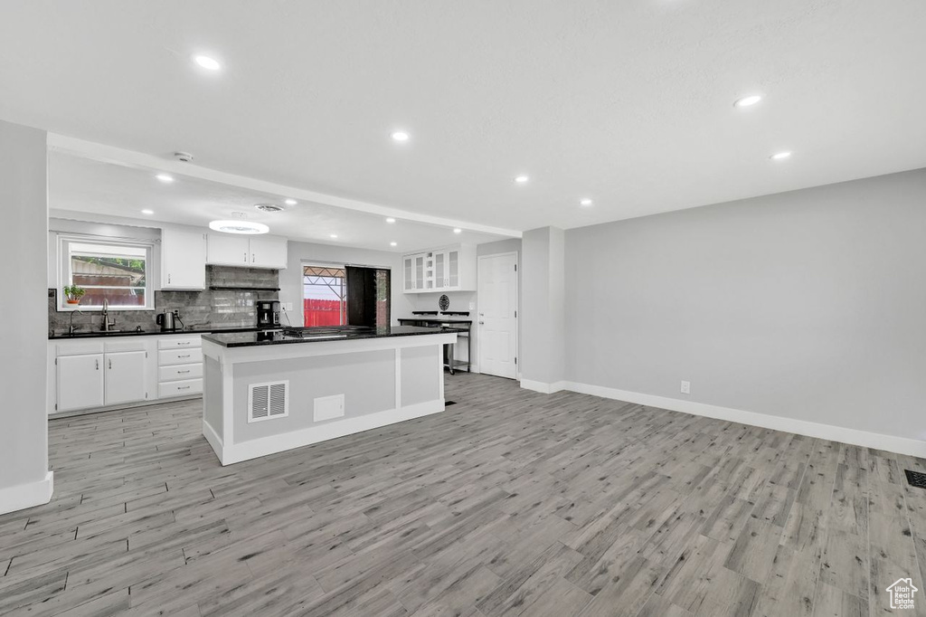 Kitchen with dark countertops, recessed lighting, light wood-style floors, and white cabinets