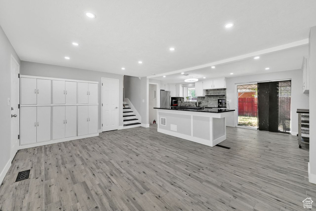 Kitchen with recessed lighting, freestanding refrigerator, dark countertops, white cabinetry, and open floor plan