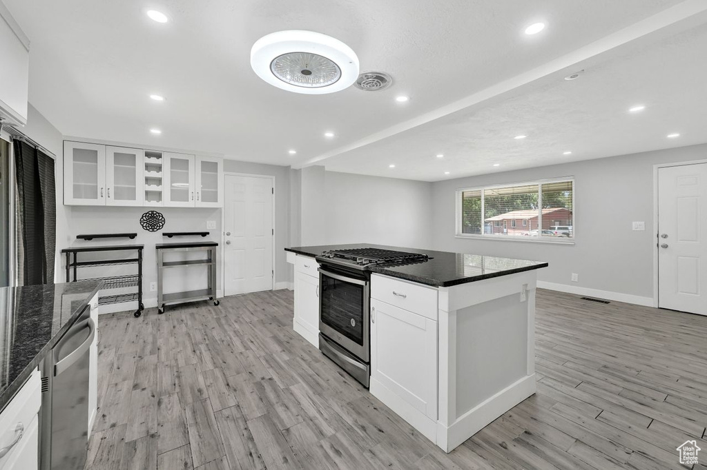 Kitchen with appliances with stainless steel finishes, light wood-style flooring, white cabinets, recessed lighting, and baseboards