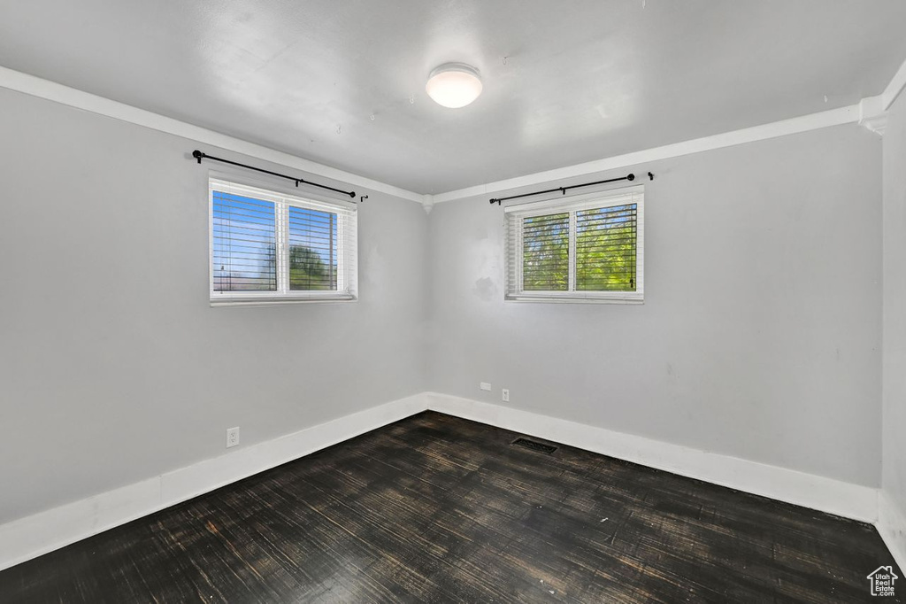 Unfurnished room with baseboards, healthy amount of natural light, dark wood-style floors, and ornamental molding