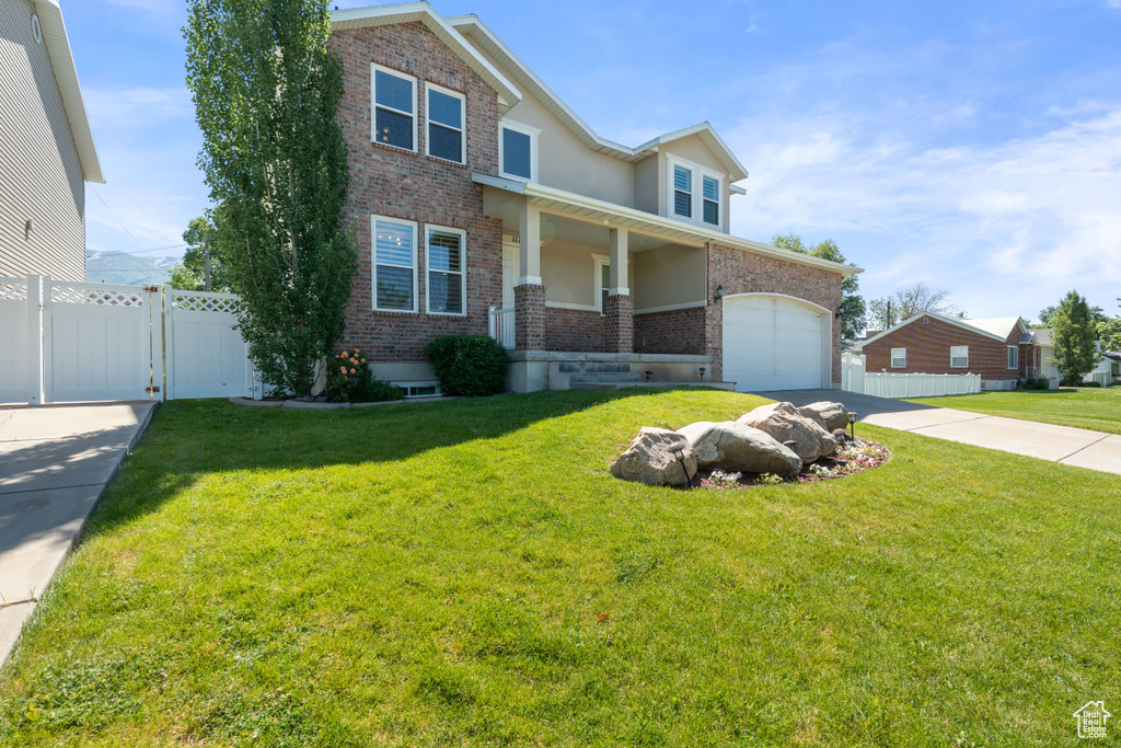 View of front of house with brick siding, driveway, a garage, stucco siding, and a porch