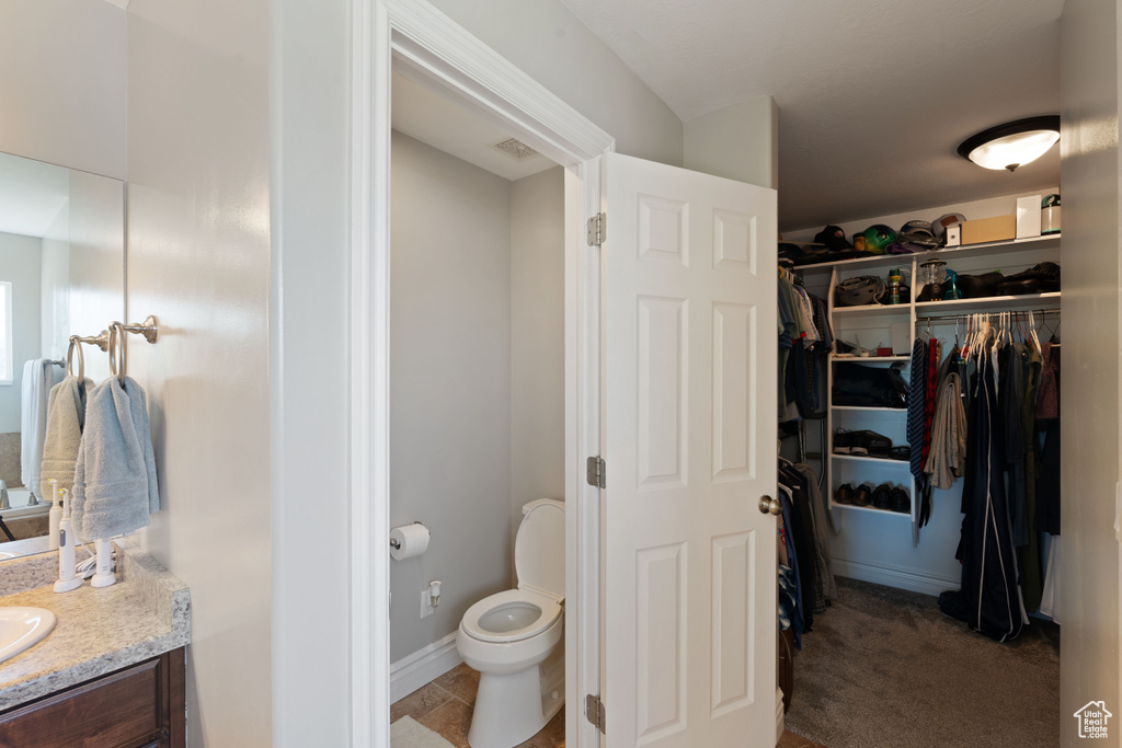 Bathroom featuring vanity, toilet, and a walk in closet