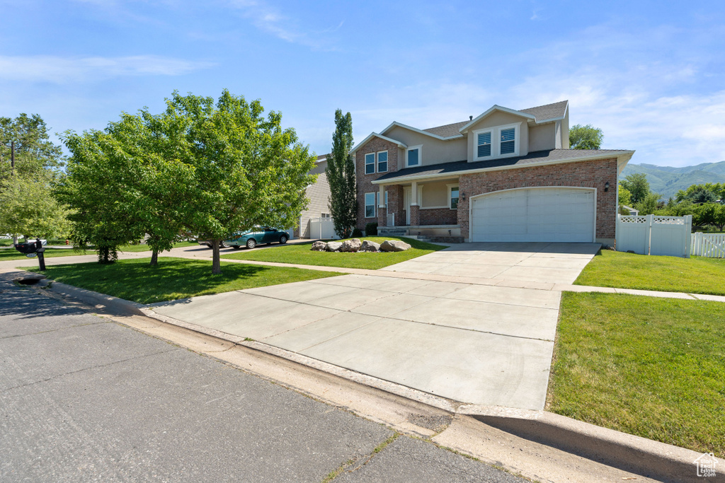 Traditional home with concrete driveway, a garage, brick siding, and a mountain view