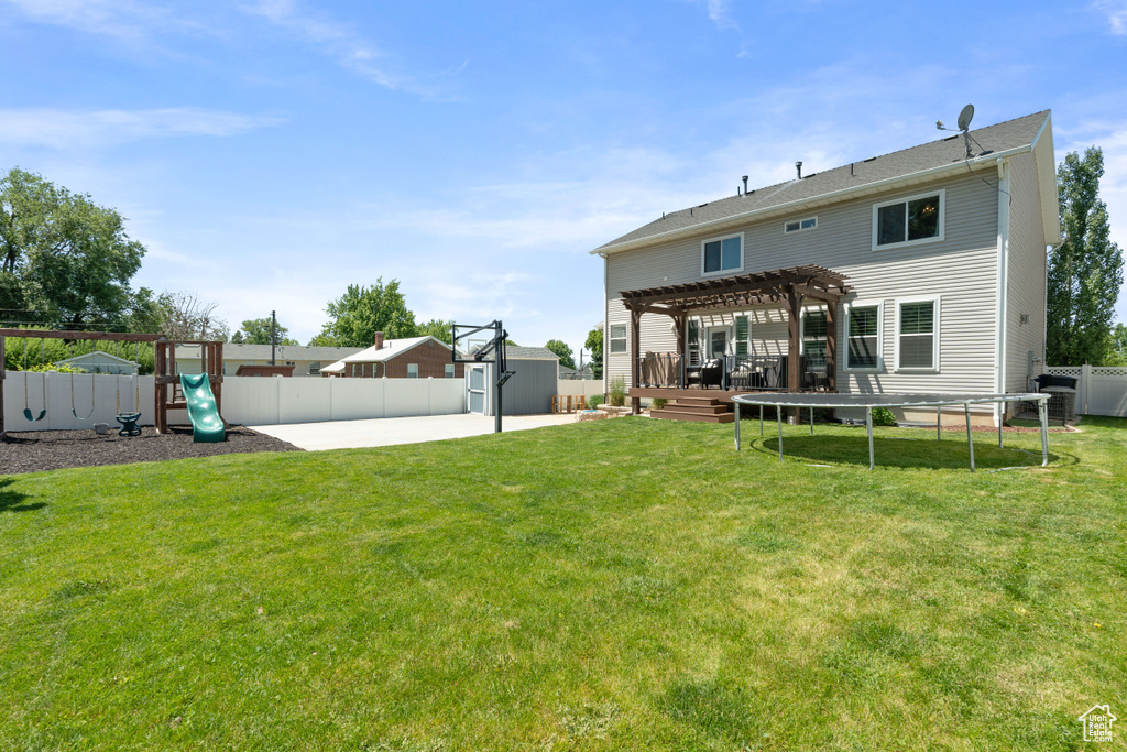 Rear view of house featuring a pergola, a trampoline, a playground, and a patio