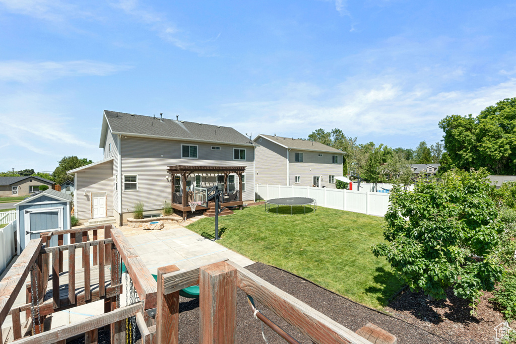 Back of house with a trampoline, a deck, and a residential view