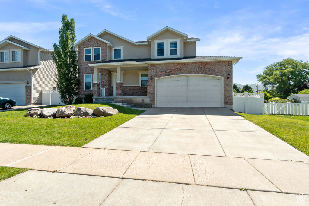 View of front of house with an attached garage, driveway, stucco siding, brick siding, and a porch