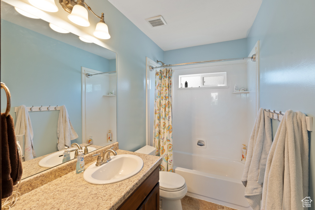 Full bath featuring toilet, shower / bath combo with shower curtain, and vanity