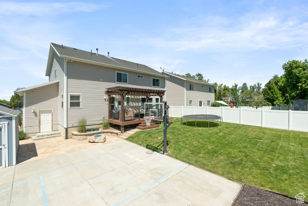 Rear view of house with a patio, a deck, a trampoline, and a pergola