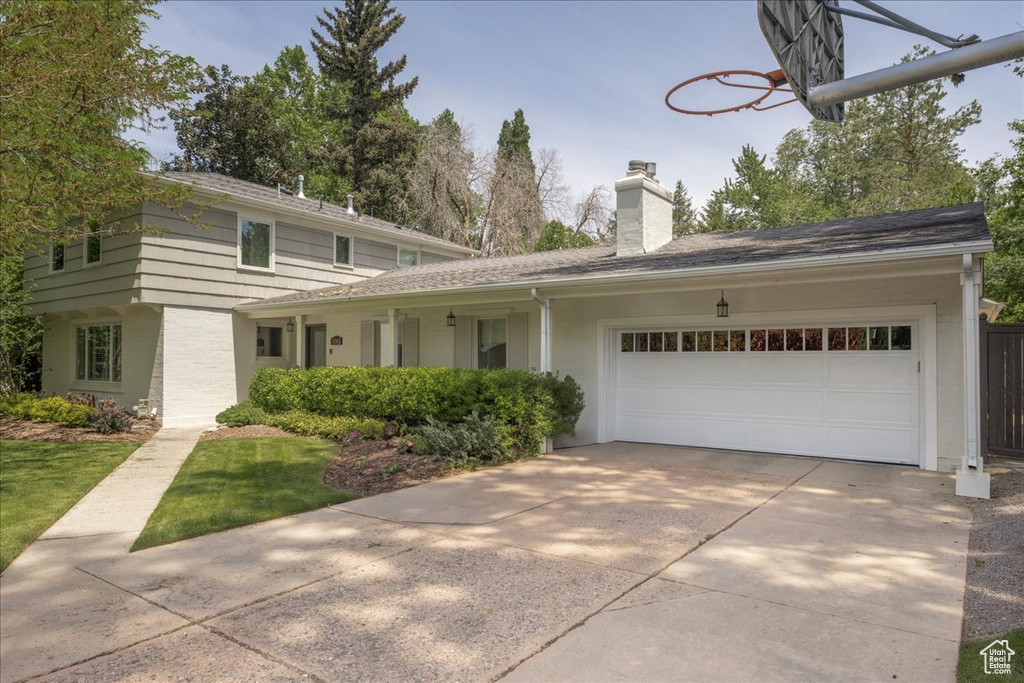 View of front of property with a chimney, an attached garage, and driveway