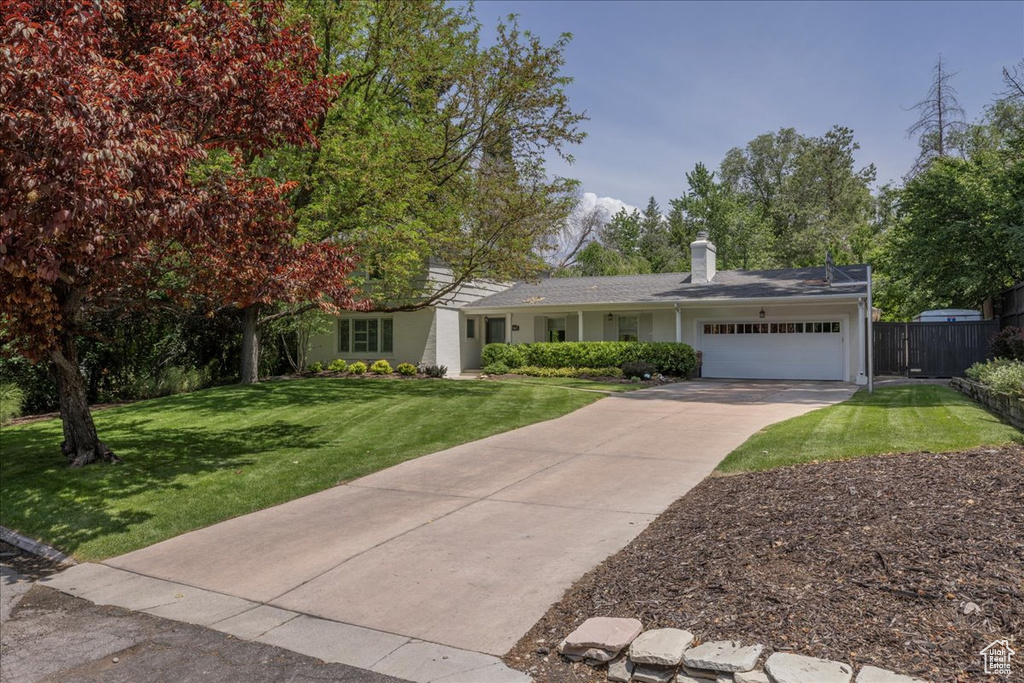View of front of property featuring an attached garage, driveway, and a chimney