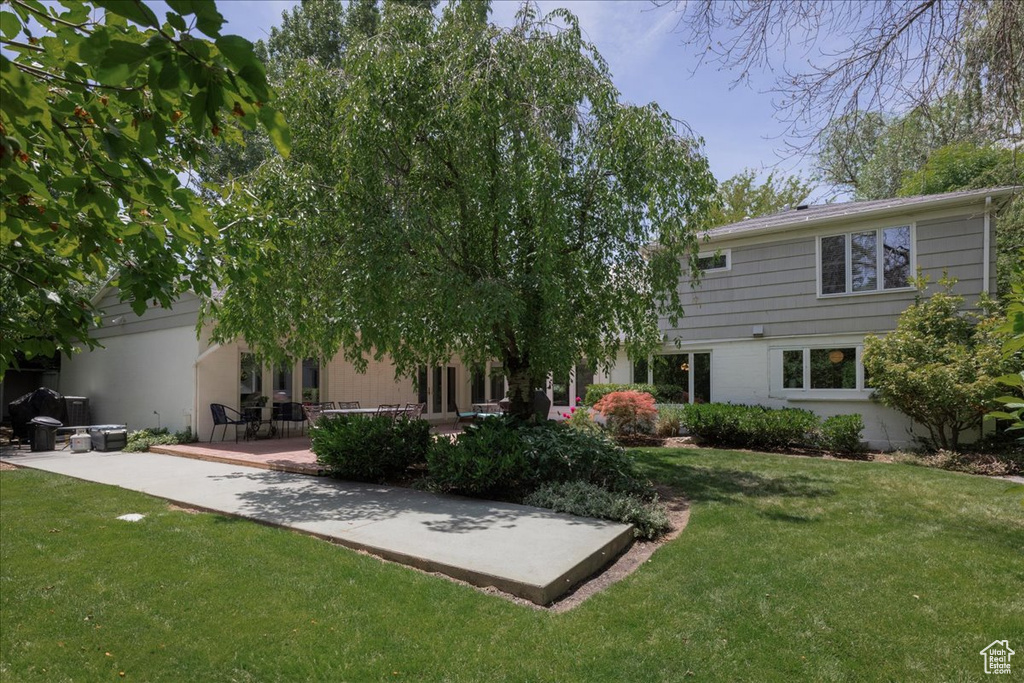 Rear view of house with a lawn and a patio