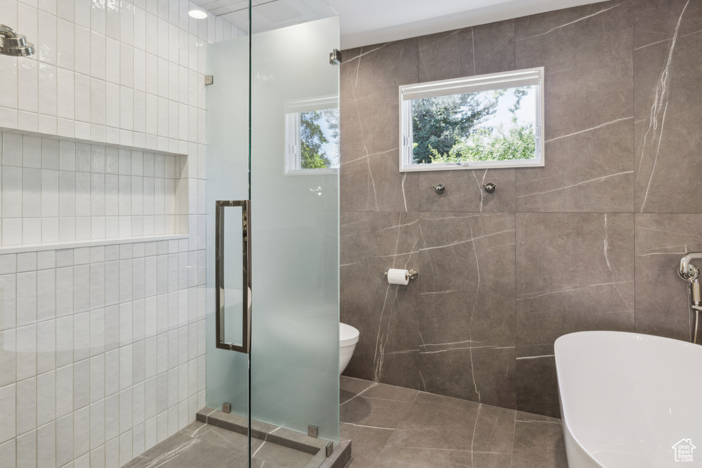 Bathroom featuring tile walls, a stall shower, a freestanding bath, and tile patterned floors