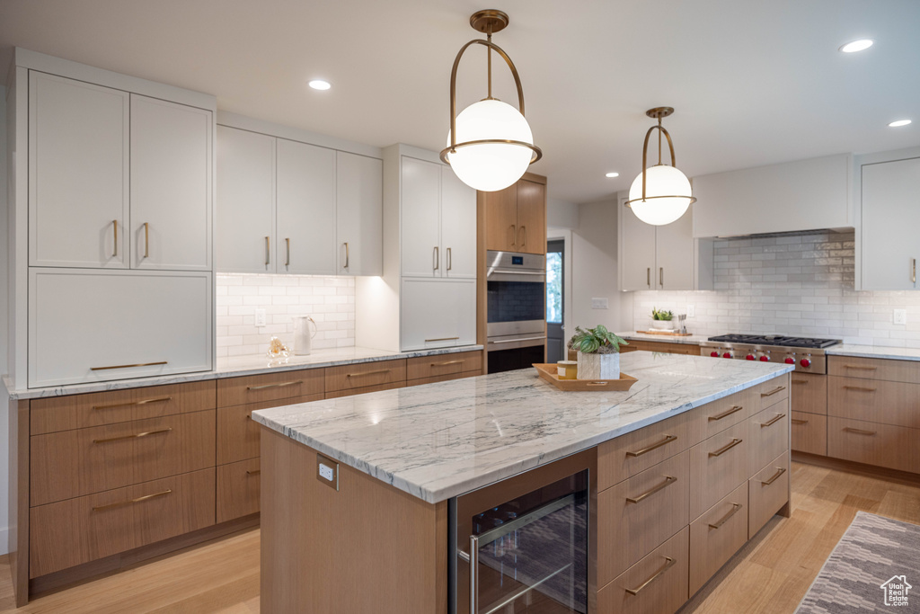 Kitchen featuring wine cooler, decorative light fixtures, white cabinets, and appliances with stainless steel finishes