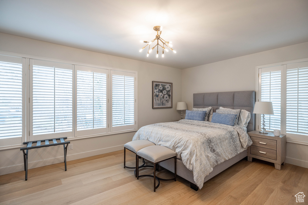 Bedroom with light hardwood / wood-style flooring and a notable chandelier