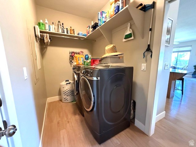 Laundry area featuring separate washer and dryer, light wood finished floors, and baseboards