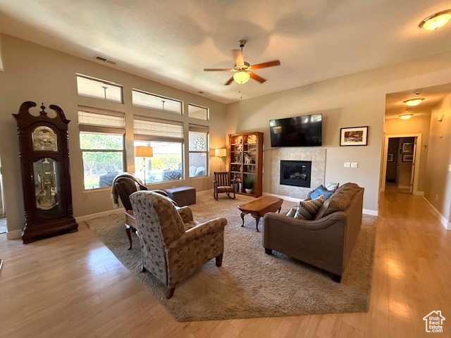 Living area featuring a tile fireplace, wood finished floors, a ceiling fan, and baseboards