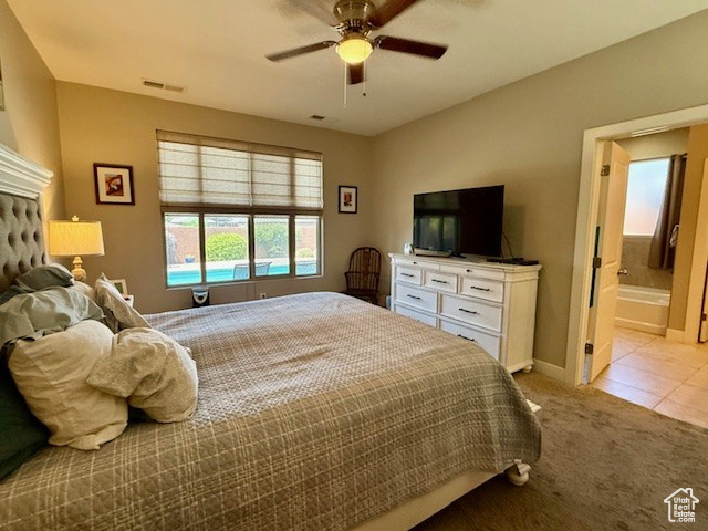 Bedroom featuring light carpet, baseboards, light tile patterned floors, ensuite bathroom, and ceiling fan
