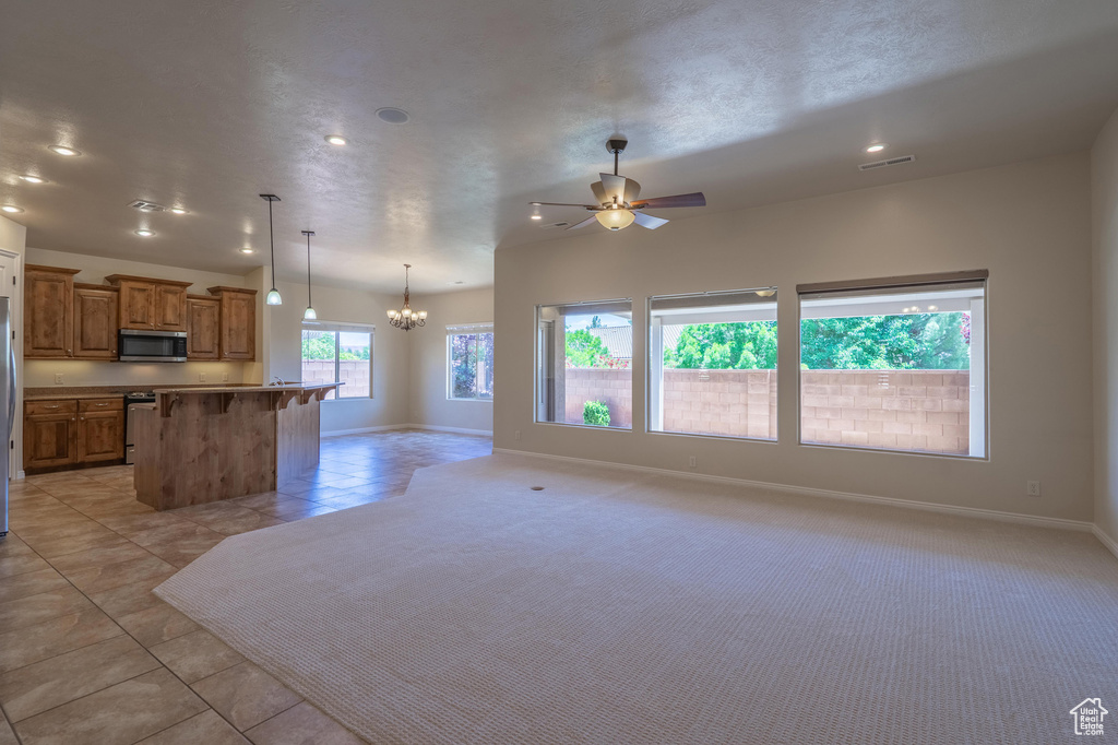 Kitchen featuring stainless steel appliances, open floor plan, brown cabinetry, a chandelier, and recessed lighting