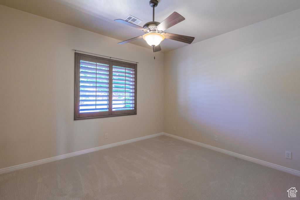 Empty room with light colored carpet, baseboards, and a ceiling fan