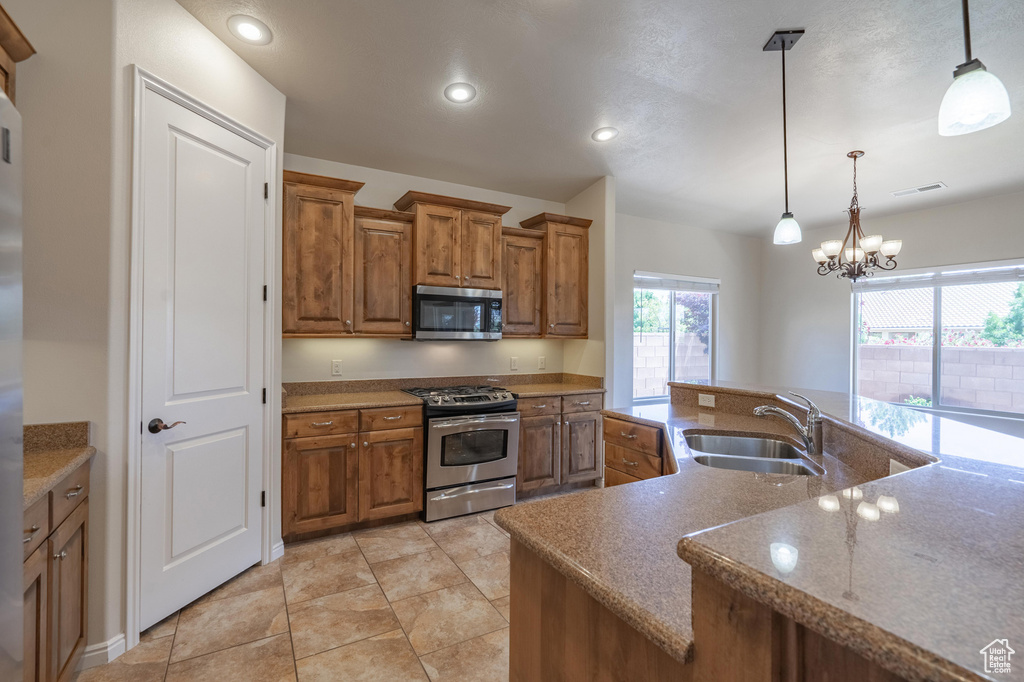 Kitchen featuring stainless steel appliances, brown cabinetry, a sink, pendant lighting, and recessed lighting