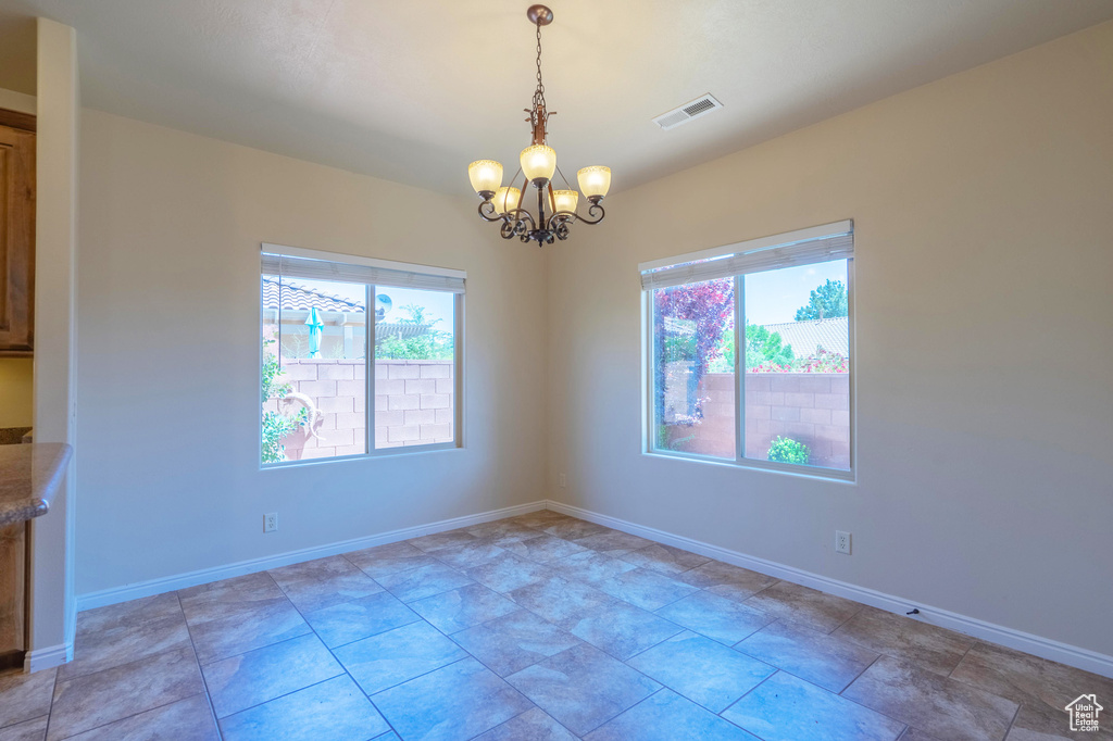 Unfurnished room with a chandelier and baseboards